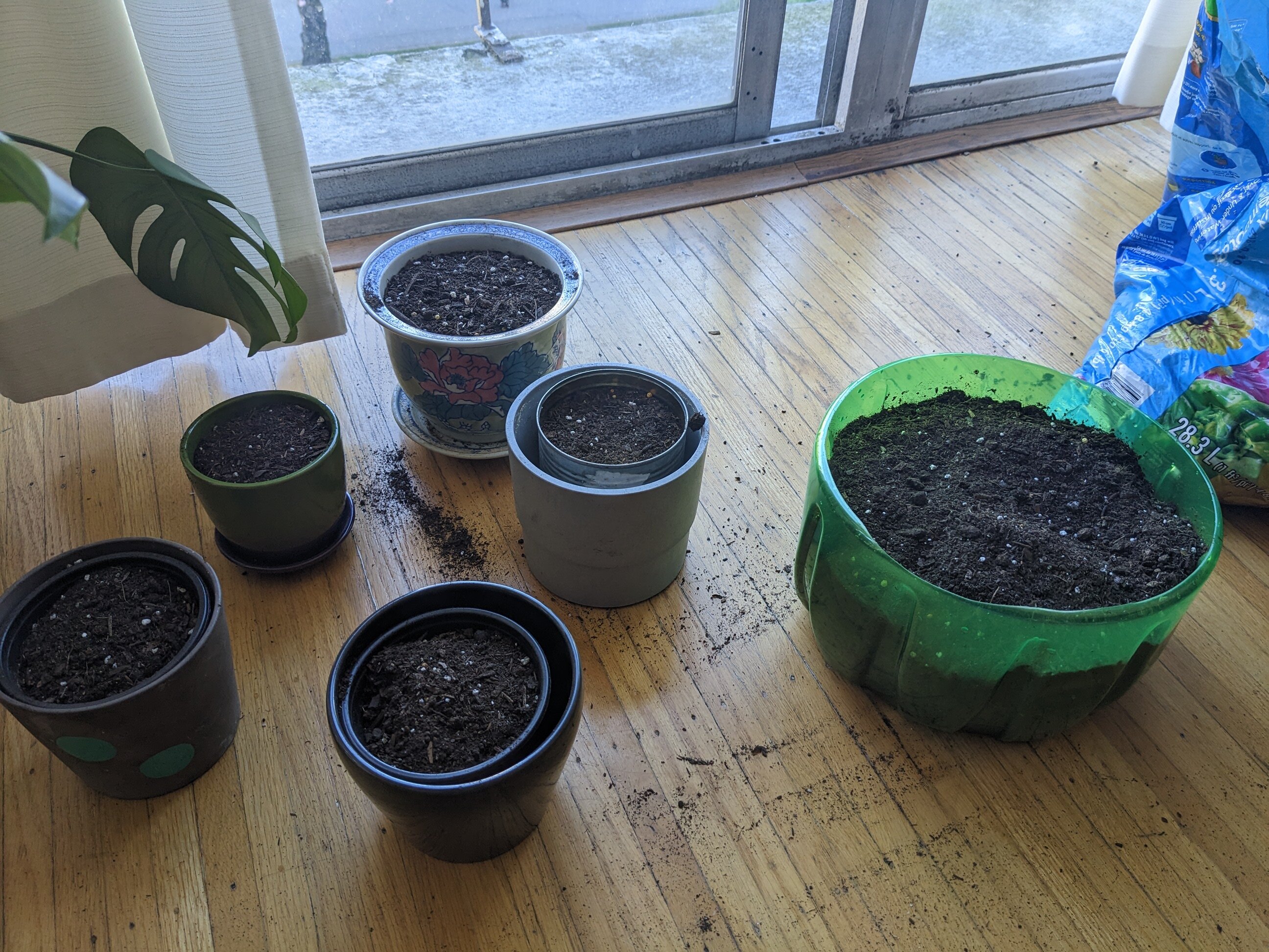 Several plant pots of varying sizes and materials, each full of soil.